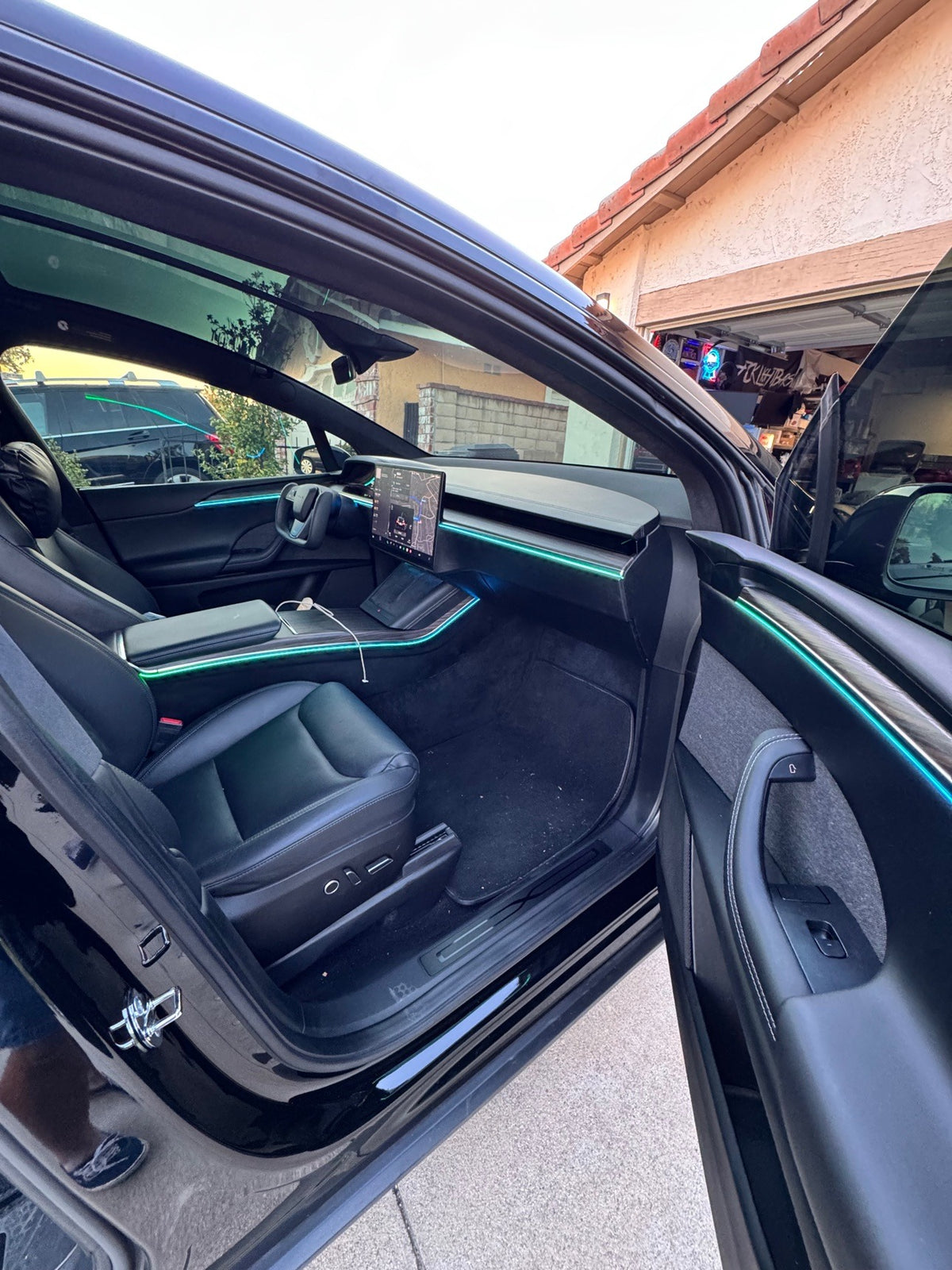 Tesla Model X front cabin with teal ambient lighting on the dashboard, center console and doors