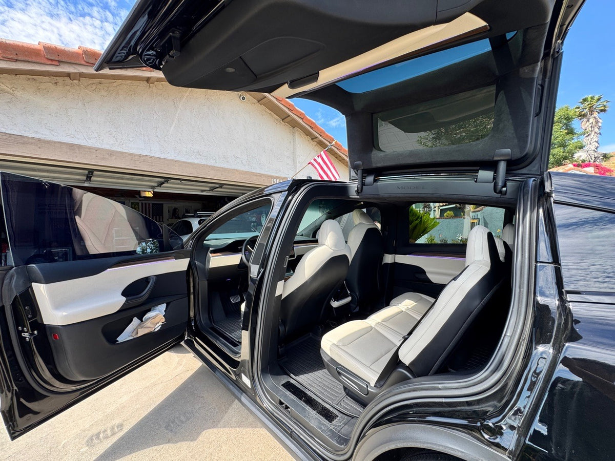 Tesla Model X falcon wing door open, white interior with ambient lighting